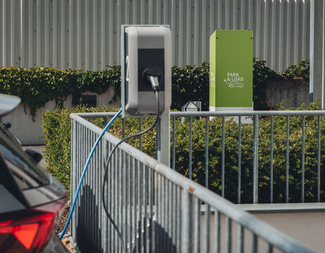 Ein Auto wird an einer Ladestation für Elektrofahrzeuge neben einem grünen Park & Load-Schild aufgeladen.